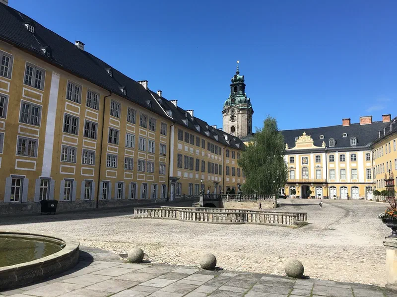 Cour intérieure du château de Heidecksburg à Rudolstadt : ailes baroques jaunes au toit gris, tour du château coiffée d&rsquo;un dôme vert et ciel bleu